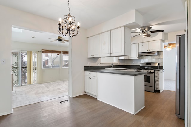 kitchen with appliances with stainless steel finishes, tasteful backsplash, white cabinets, hardwood / wood-style flooring, and ceiling fan