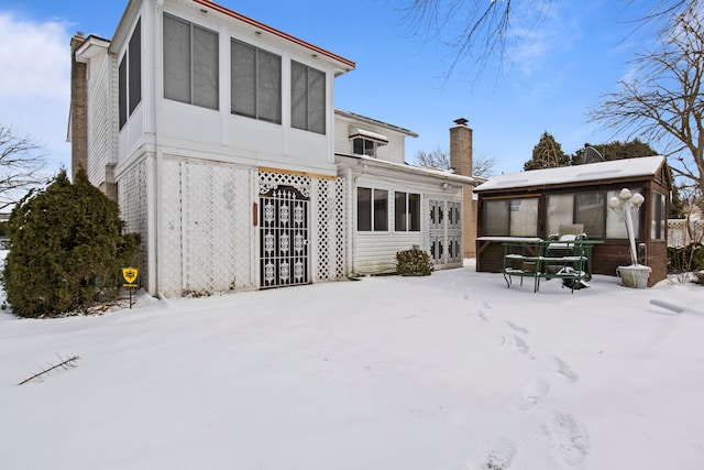 snow covered back of property with a jacuzzi