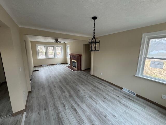 unfurnished living room with light hardwood / wood-style flooring and a textured ceiling