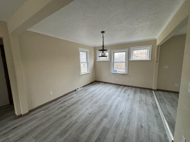 unfurnished dining area featuring a textured ceiling and light wood-type flooring