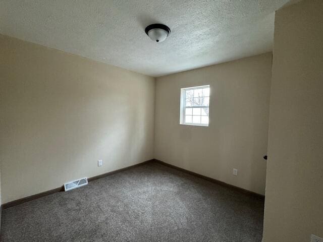 unfurnished room with a textured ceiling and dark colored carpet