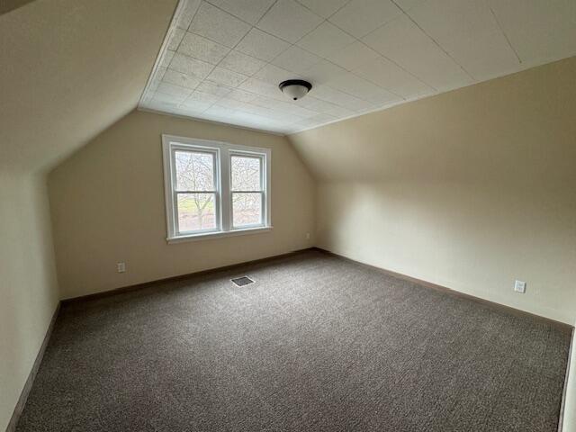 bonus room with lofted ceiling and carpet flooring