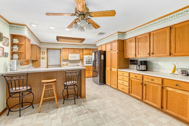 kitchen with a breakfast bar, crown molding, ceiling fan, kitchen peninsula, and white appliances