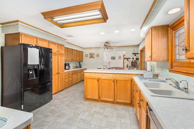 kitchen with sink, ornamental molding, ceiling fan, kitchen peninsula, and black fridge