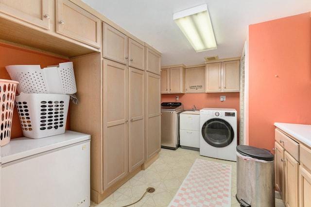 clothes washing area featuring independent washer and dryer and cabinets