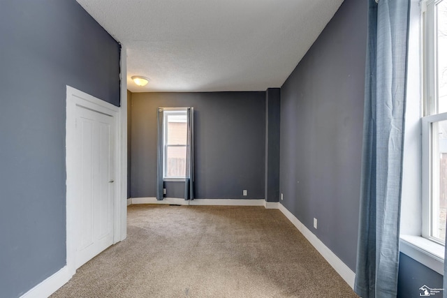 carpeted empty room with a textured ceiling