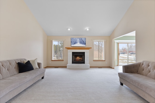 carpeted living room featuring a brick fireplace and high vaulted ceiling