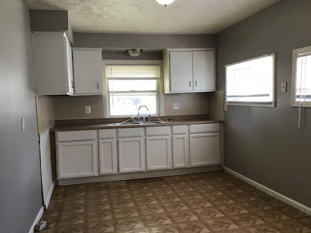 kitchen featuring light parquet flooring, sink, and white cabinets