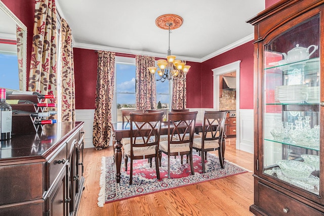 dining space featuring an inviting chandelier, crown molding, and light hardwood / wood-style flooring