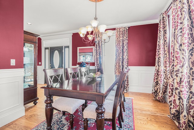 dining room featuring an inviting chandelier, light hardwood / wood-style flooring, and ornamental molding