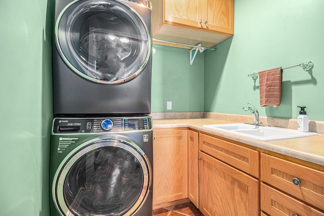 laundry area featuring stacked washer and dryer, sink, and cabinets