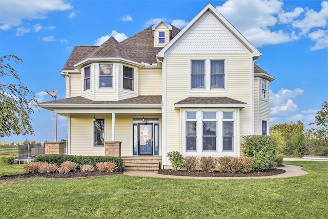 view of front of property featuring a trampoline, a front yard, and a porch