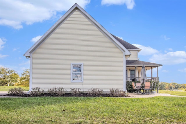 view of side of home with a patio and a lawn