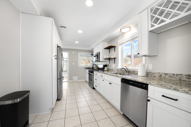 kitchen featuring light stone countertops, appliances with stainless steel finishes, light tile patterned floors, and white cabinets