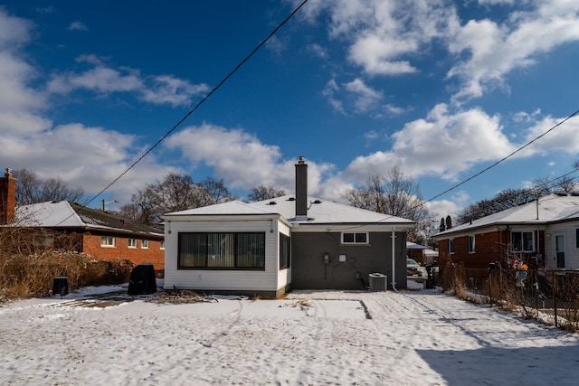 snow covered rear of property featuring central AC