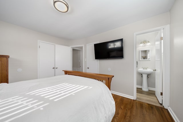 bedroom with dark wood-type flooring, ensuite bathroom, sink, and a closet