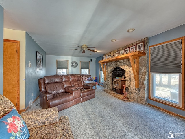 living room featuring carpet floors, a wood stove, and ceiling fan