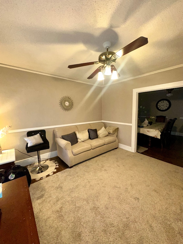 living room with ceiling fan, ornamental molding, carpet flooring, and a textured ceiling