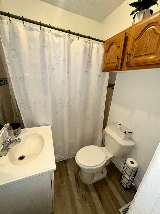 bathroom featuring wood-type flooring, toilet, a textured ceiling, and vanity