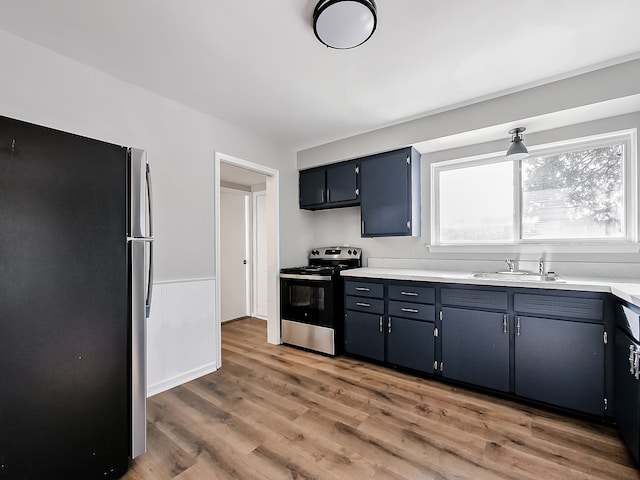 kitchen with blue cabinets, sink, hardwood / wood-style flooring, and appliances with stainless steel finishes