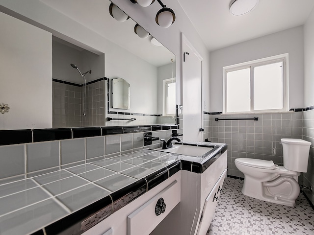 bathroom featuring vanity, tile walls, and toilet