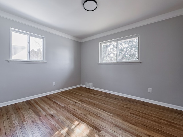 empty room featuring ornamental molding and hardwood / wood-style floors