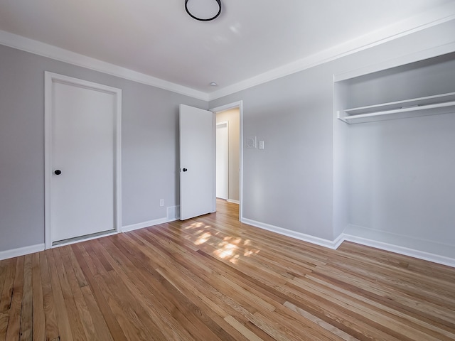 unfurnished bedroom featuring crown molding, light hardwood / wood-style flooring, and a closet