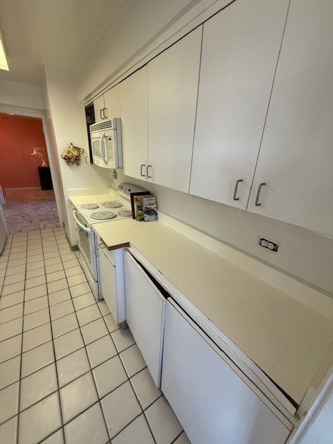 kitchen featuring white cabinetry, white appliances, light tile patterned floors, and light countertops