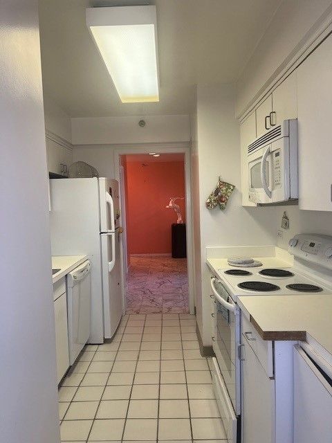 kitchen featuring light tile patterned flooring, white cabinets, white appliances, and light countertops