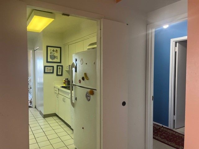 kitchen with white cabinetry, light tile patterned floors, and freestanding refrigerator