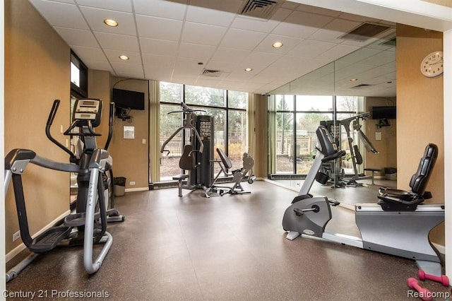 gym with a wall of windows, a paneled ceiling, visible vents, and baseboards