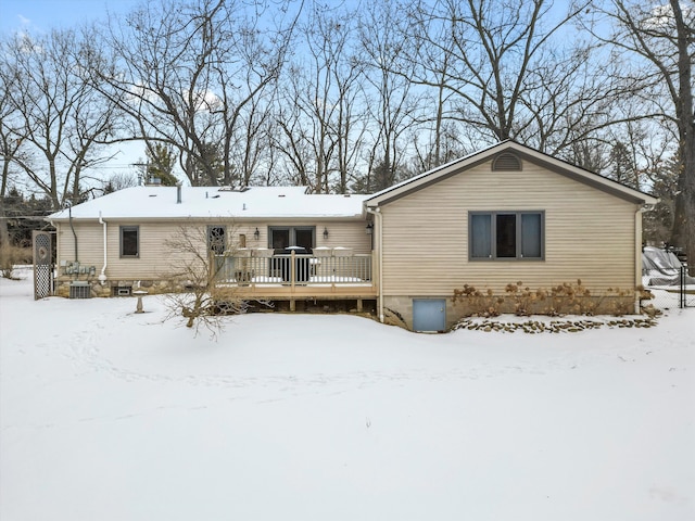 snow covered house featuring a wooden deck