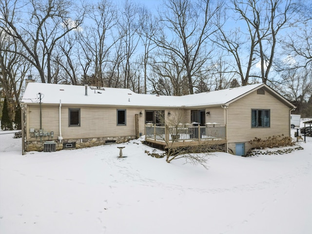 snow covered back of property with central AC unit and a deck