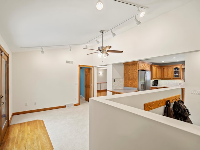 kitchen with ceiling fan, decorative backsplash, vaulted ceiling, light carpet, and stainless steel fridge