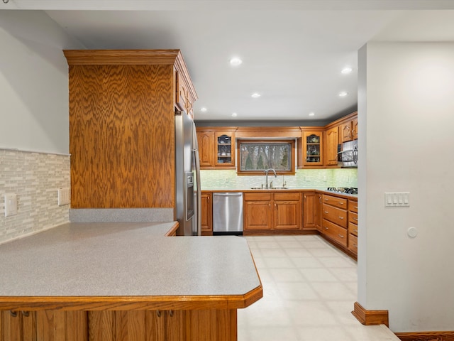 kitchen featuring appliances with stainless steel finishes, sink, backsplash, and kitchen peninsula