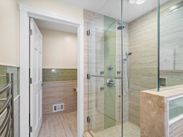 bathroom featuring a shower with shower door and tile walls