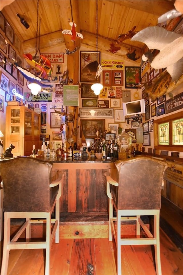 bar featuring wood-type flooring, vaulted ceiling with beams, wooden ceiling, and decorative light fixtures