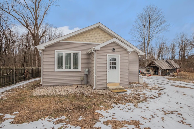 snow covered rear of property with an outdoor structure