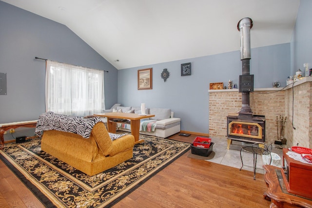 living room featuring hardwood / wood-style flooring, vaulted ceiling, a wood stove, and electric panel