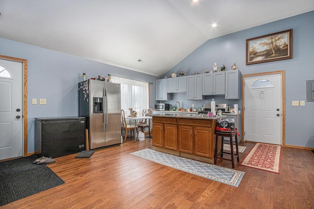 kitchen with a center island, stainless steel fridge with ice dispenser, a kitchen breakfast bar, gray cabinets, and light hardwood / wood-style floors