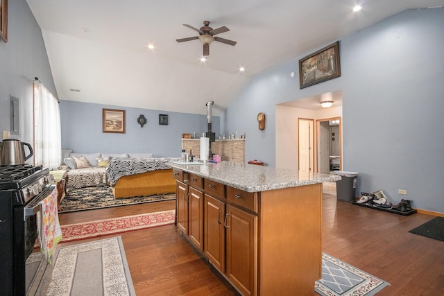 kitchen featuring a kitchen island, range with gas stovetop, lofted ceiling, dark hardwood / wood-style flooring, and light stone countertops