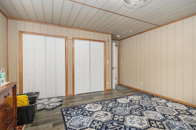 bedroom featuring multiple closets, wooden ceiling, and dark hardwood / wood-style flooring