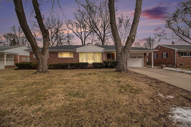 single story home with a yard, concrete driveway, brick siding, and an attached garage