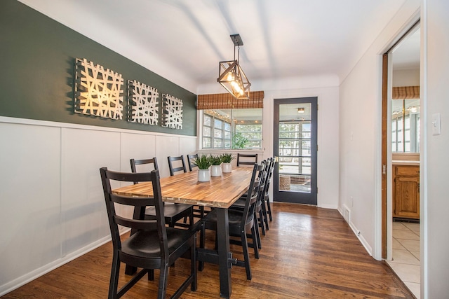 dining space featuring visible vents, a decorative wall, wood finished floors, and wainscoting