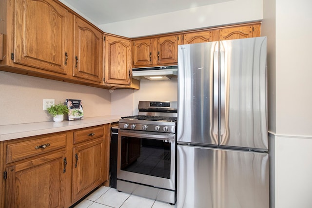 kitchen featuring light tile patterned floors, brown cabinetry, appliances with stainless steel finishes, light countertops, and under cabinet range hood