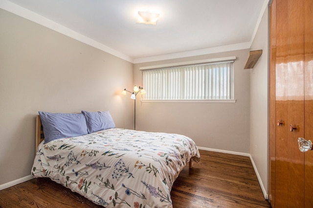 bedroom with ornamental molding, baseboards, and wood finished floors