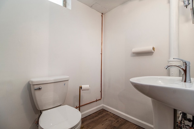 half bathroom with toilet, a sink, baseboards, and wood finished floors