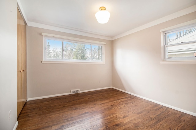 unfurnished room with wood finished floors, visible vents, and baseboards