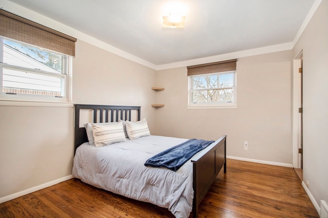 bedroom with crown molding, visible vents, baseboards, and wood finished floors