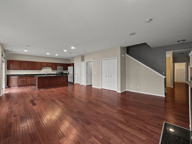 kitchen with appliances with stainless steel finishes, dark hardwood / wood-style flooring, a center island, and sink